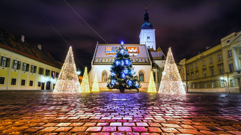 Festlich beleuchteter Weihnachtsbaum mit Lichterkegeln vor der Markuskirche in Zagreb bei Nacht.