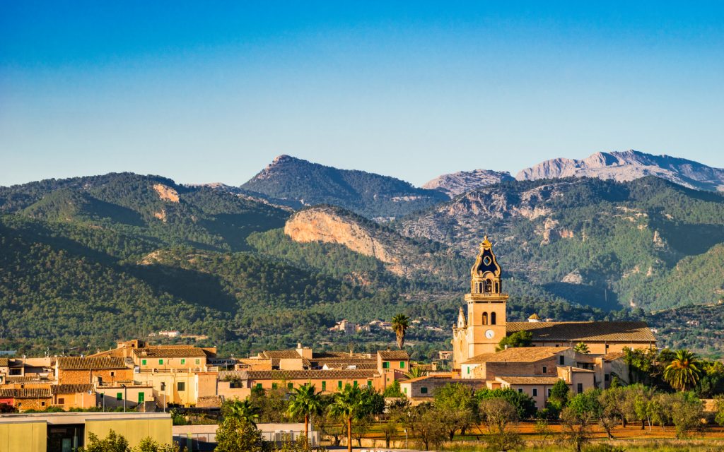 Panorama von Santa Maria del Cami auf Mallorca mit Kirchturm und Tramuntana-Gebirge im Hintergrund.