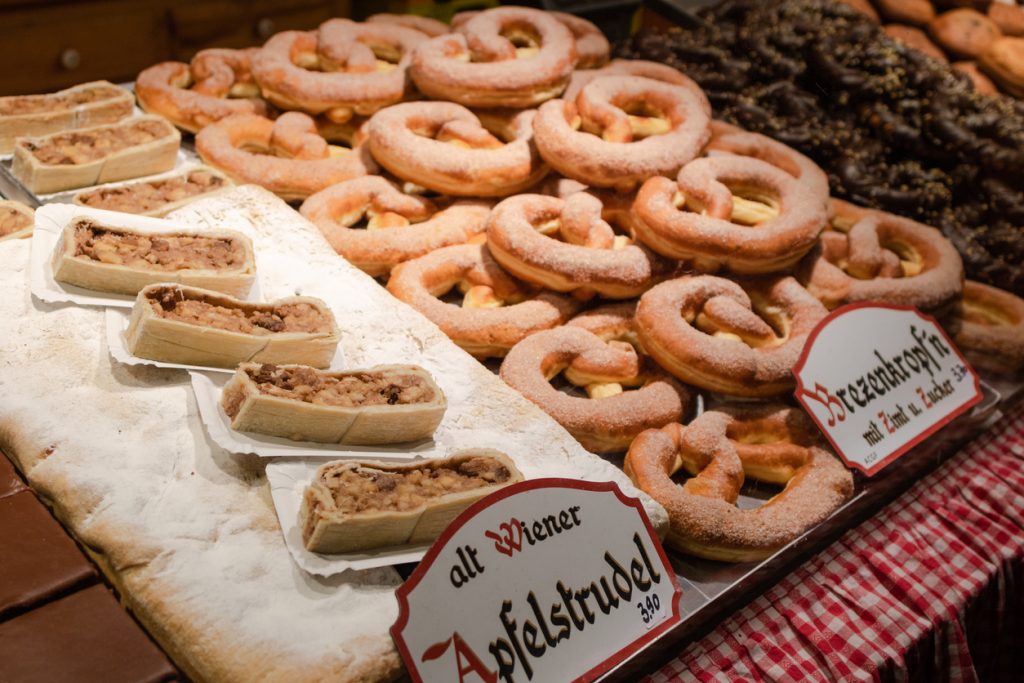 Auslage mit Apfelstrudelstücken und gezuckerten Bretzelkrapfen an einem Wiener Stand.