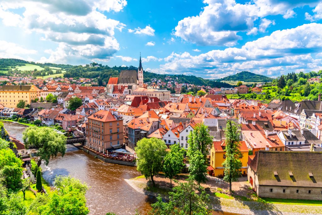 Altstadt von Český Krumlov mit roten Dächern, Kirche und Fluss im Vordergrund.