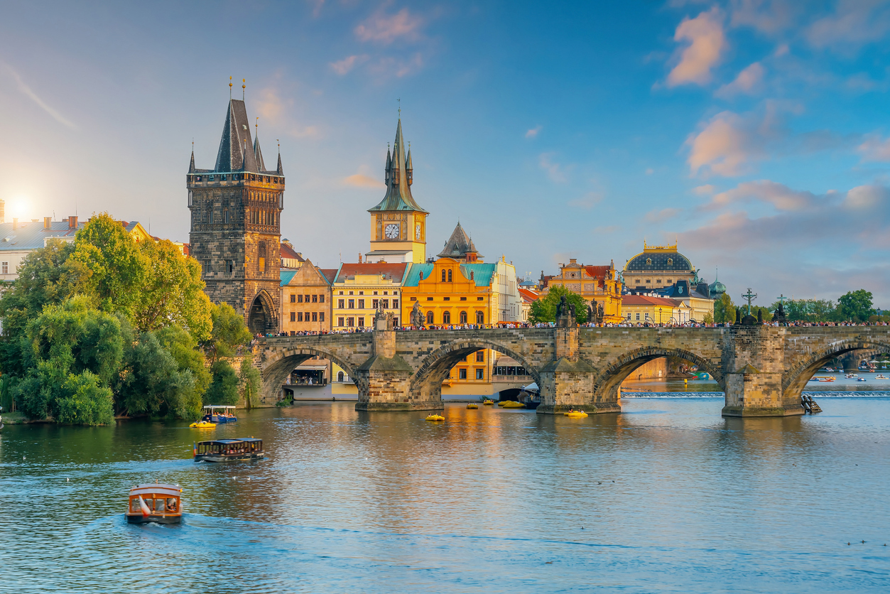 Die Karlsbrücke in Prag spannt sich über die Moldau, daneben ragen historische Türme und Dächer auf.