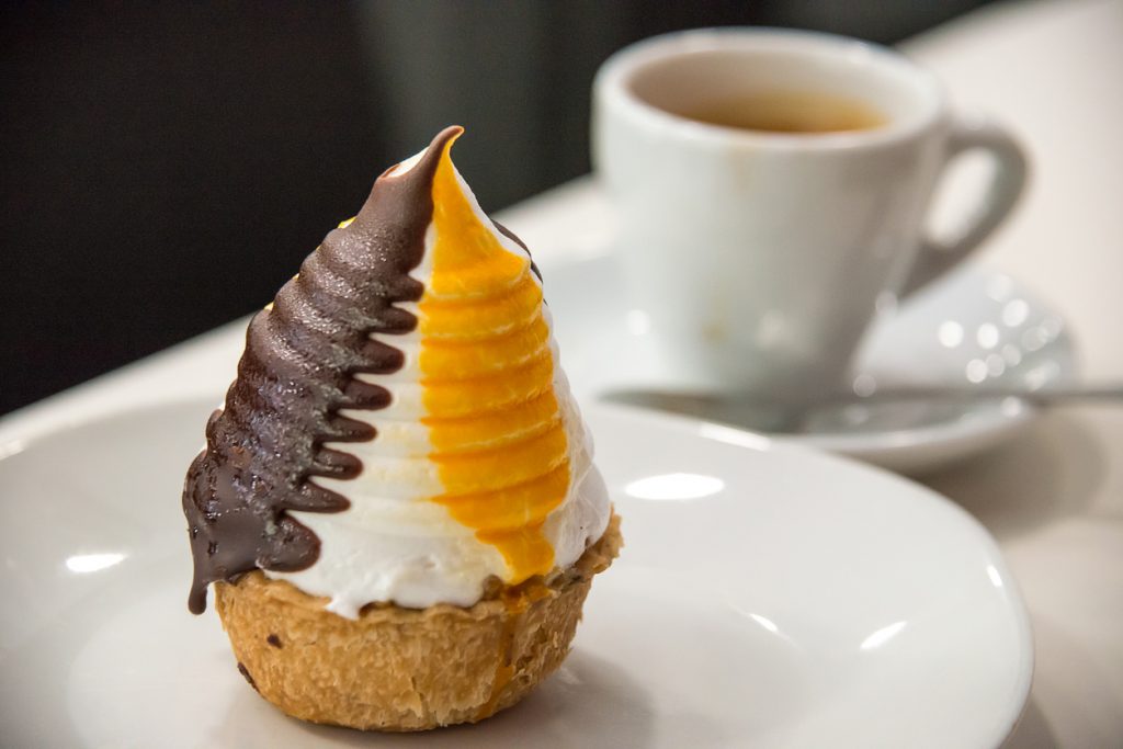 Ein kleines Gebäck mit Creme und Schoko neben einer Tasse Kaffee in Bilbao.