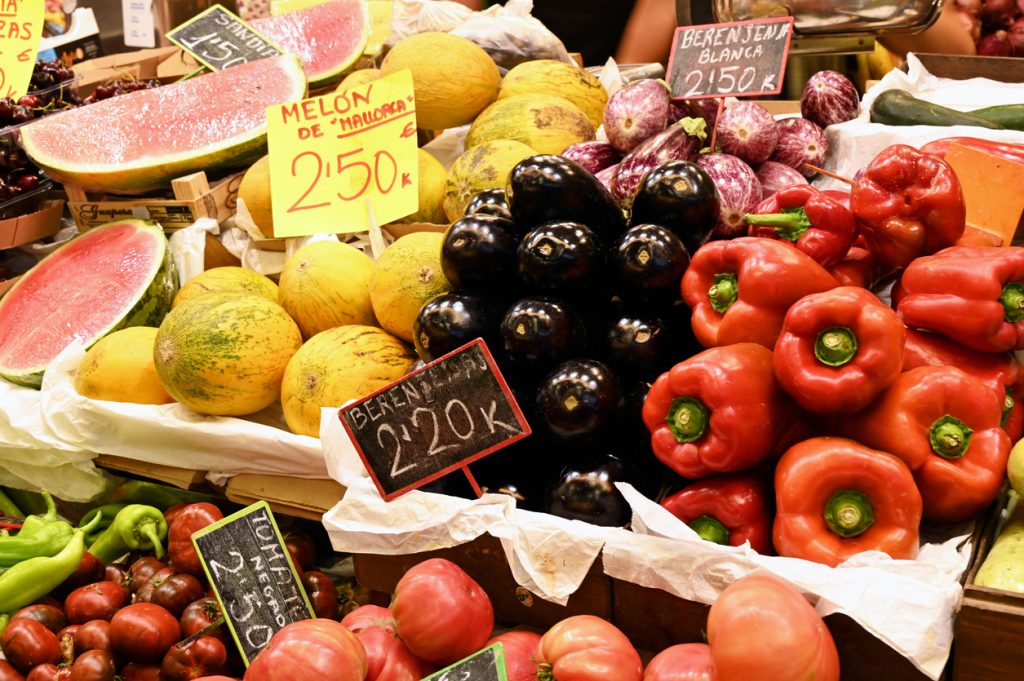 Melonen, Auberginen, Tomaten und rote Paprika liegen dicht gestapelt im Mercat de l’Olivar.