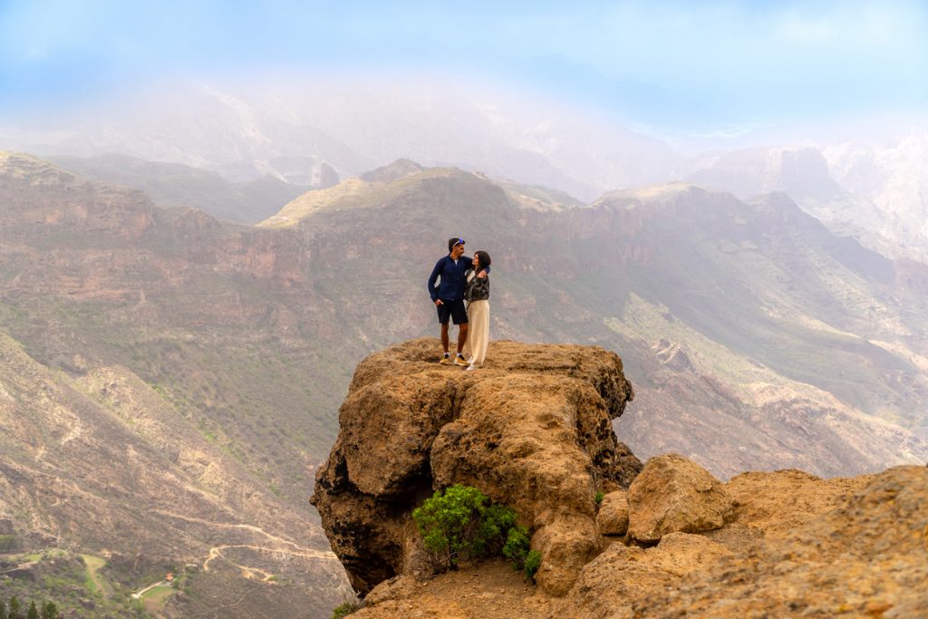 Ein Paar steht auf einem Felsvorsprung und blickt in eine weite Schlucht.