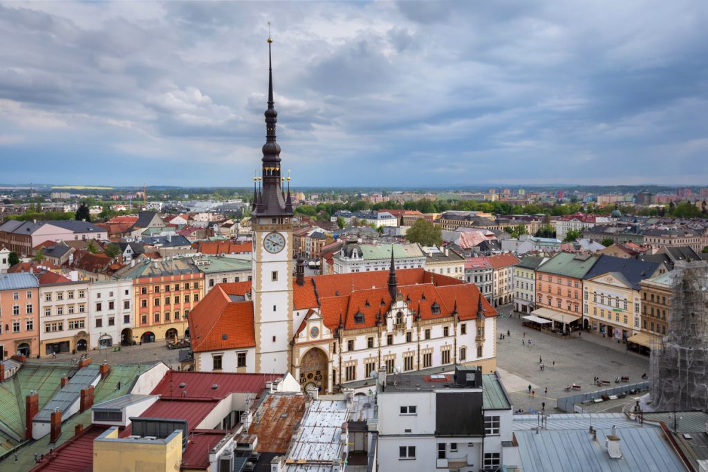 Olmütz von oben mit hohem Rathausturm, bunten Häusern und weitem Marktplatz unter Wolken.