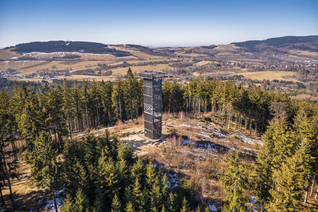 Hoher Aussichtsturm steht am Waldrand mit Blick über Hügel und Dörfer in Tschechien.
