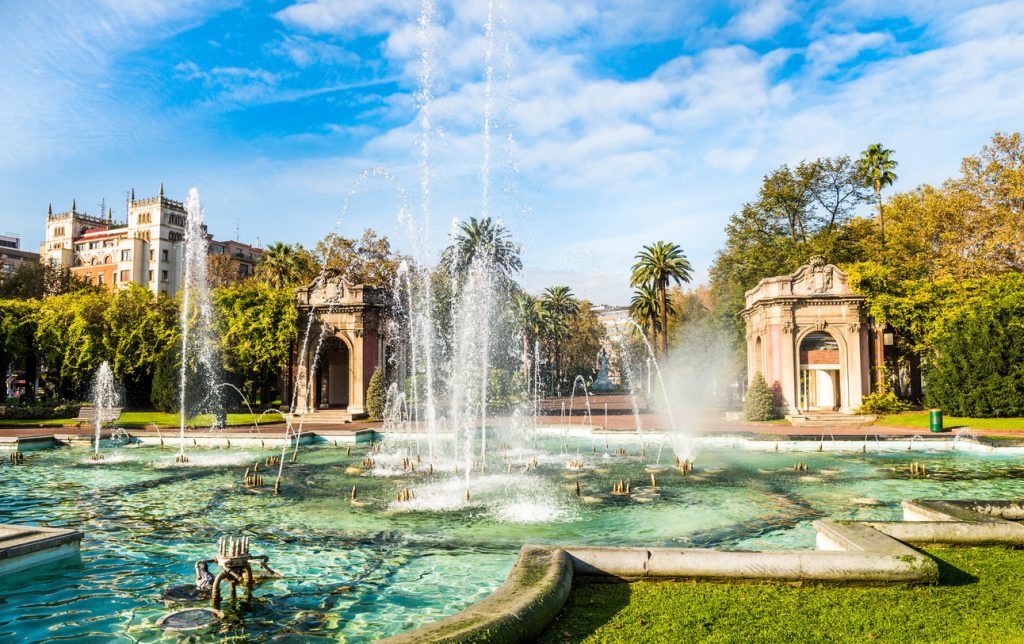 Ein großer Springbrunnen in einem Park in Bilbao mit Palmen und Pavillons.