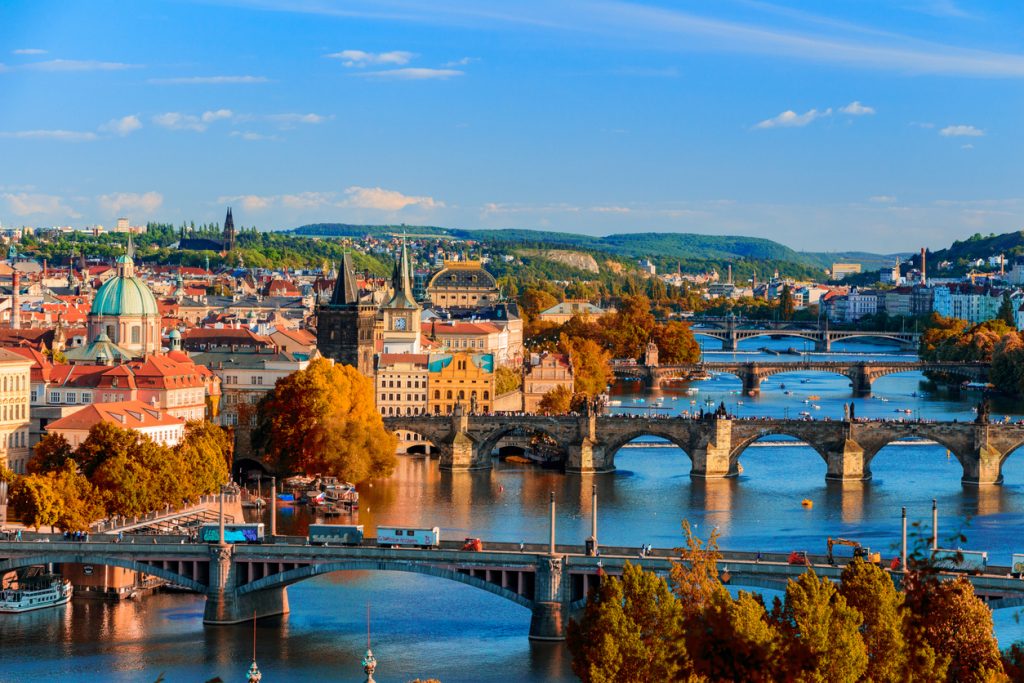 Blick über Prag mit der Karlsbrücke und der Moldau, dahinter die Altstadt und Hügel.