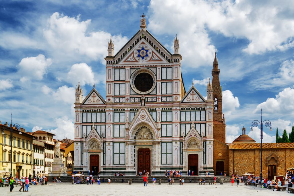 Die Basilika Santa Croce steht mit ihrer verzierten Fassade auf einem weiten Platz in Florenz.