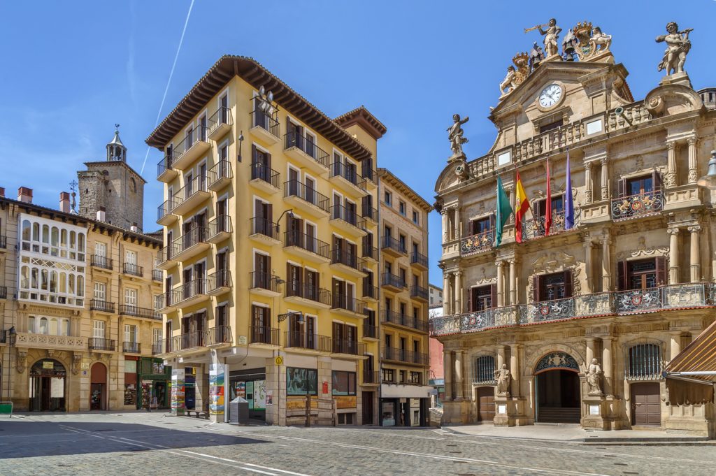 Platz mit historischen Gebäuden und Rathausfassade in Pamplona bei blauem Himmel.