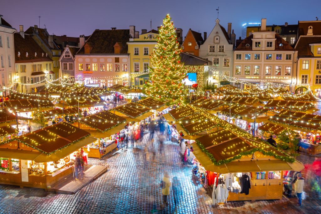 Weihnachtsmarkt bei Nacht mit großem geschmücktem Baum und beleuchteten Buden.