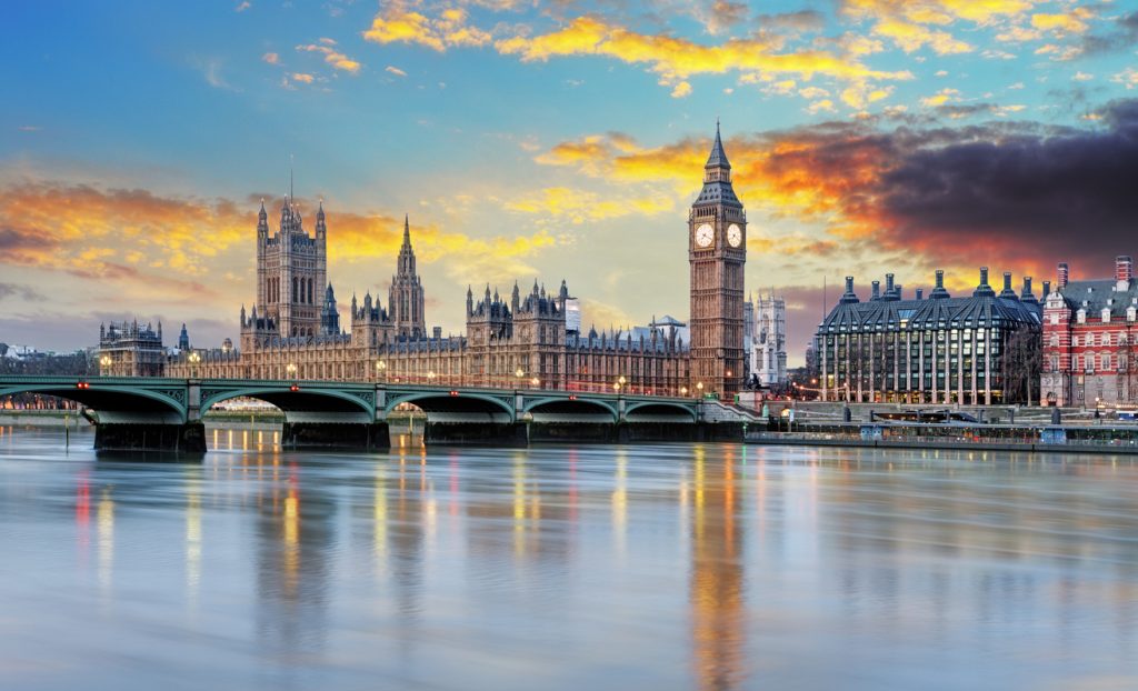 Westminster mit Big Ben und der Brücke bei warmem Licht und ruhigem Wasser.
