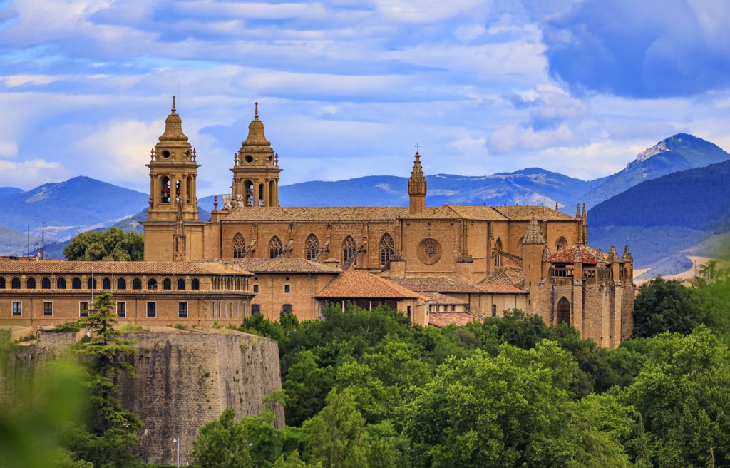 Große Kirchenanlage mit Türmen und Stadtmauer vor den Bergen bei Pamplona.