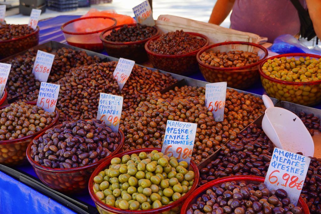 Große Schalen mit grünen und dunklen Oliven stehen dicht an dicht mit Preisschildern.