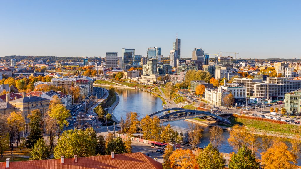 Ein Fluss schlängelt sich durch die Stadt, dahinter stehen moderne Hochhäuser und Brücken.