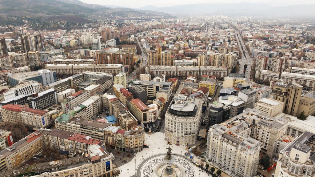 Luftaufnahme über dichte Häuserblocks und breite Straßenachsen in Skopje.
