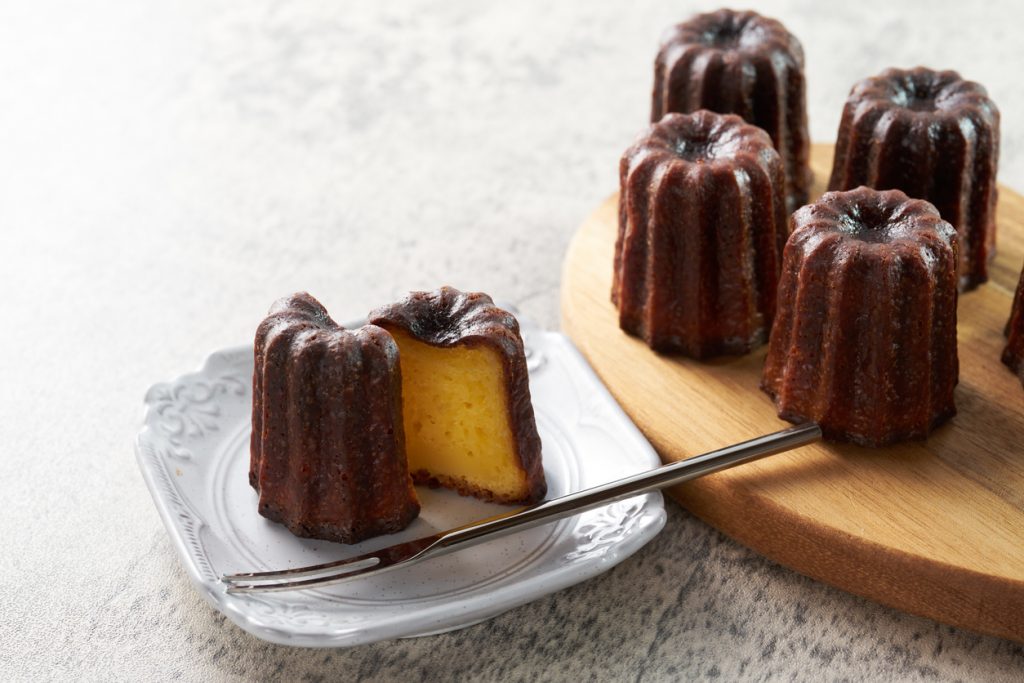 Kleine Kuchen mit karamellisierter Oberfläche auf einem Brett, einer ist aufgeschnitten