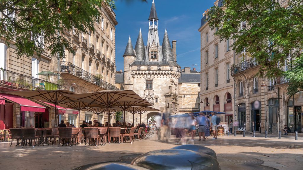 Platz mit Restaurants und Menschen vor einem historischen Stadttor