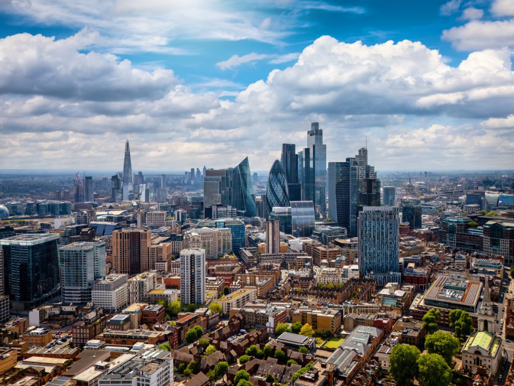 Eine weite Stadtansicht mit vielen Gebäuden und markanten Wolkenkratzern unter Wolken.
