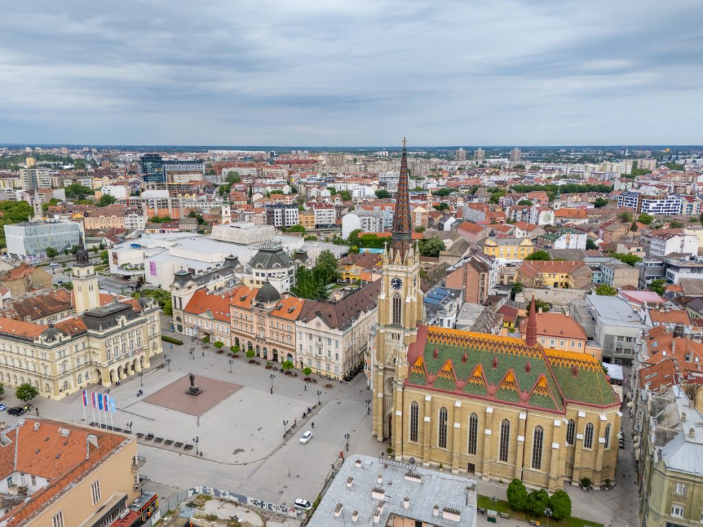 Luftaufnahme vom Zentrum von Novi Sad mit Kirche, Platz und dichter Altstadtbebauung.