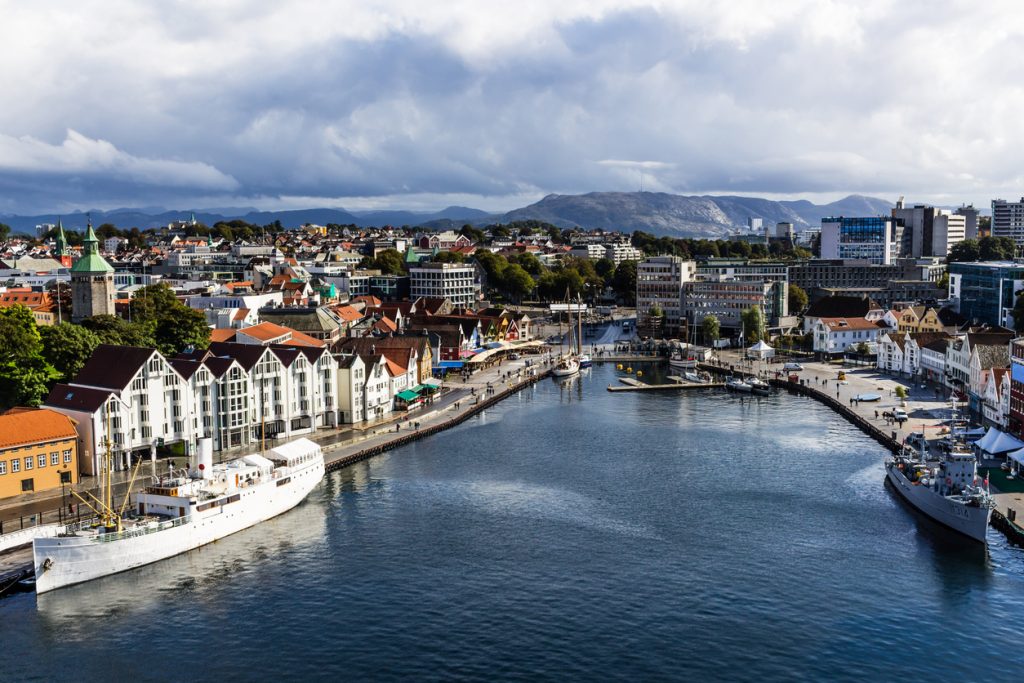 Blick auf den Hafen mit Booten, Kais, Gebäuden und dunklen Wolken über der Stadt.
