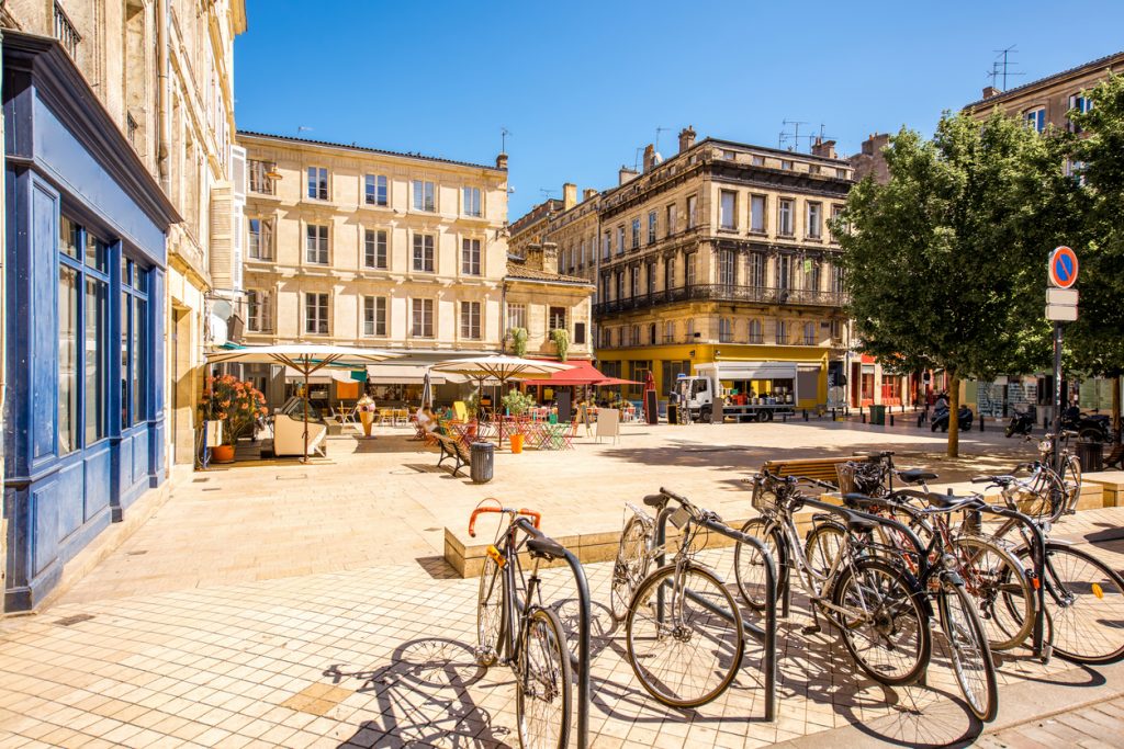 Stadtplatz mit Fahrrädern, Cafés und historischen Fassaden bei blauem Himmel