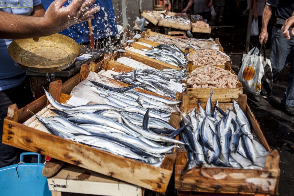 Auf einem Markt in Catania liegen frische Fische und Meeresfrüchte in Holzkisten.