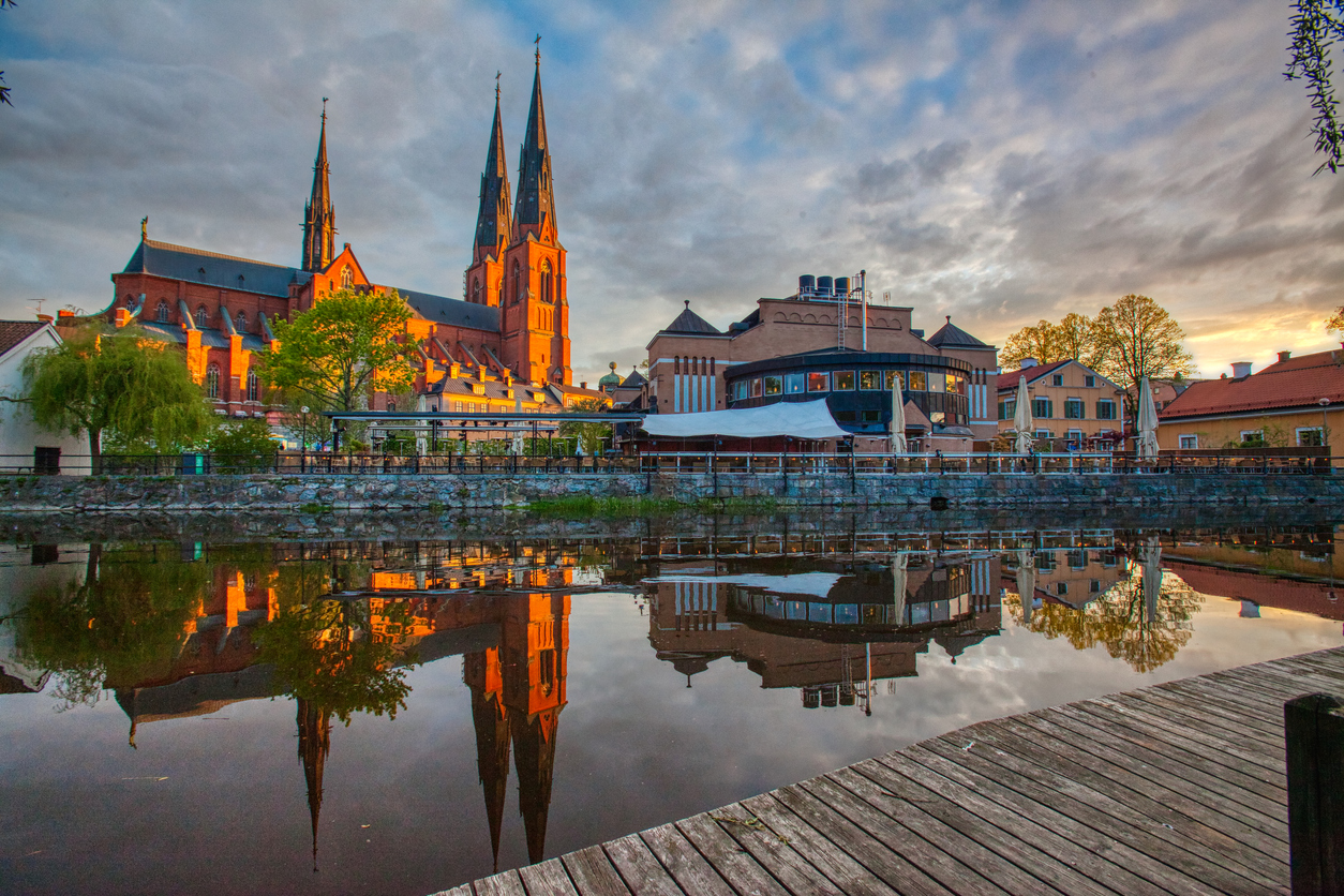 Die Silhouette des Doms von Uppsala spiegelt sich bei Sonnenuntergang im ruhigen Wasser des Flusses Fyrisån.