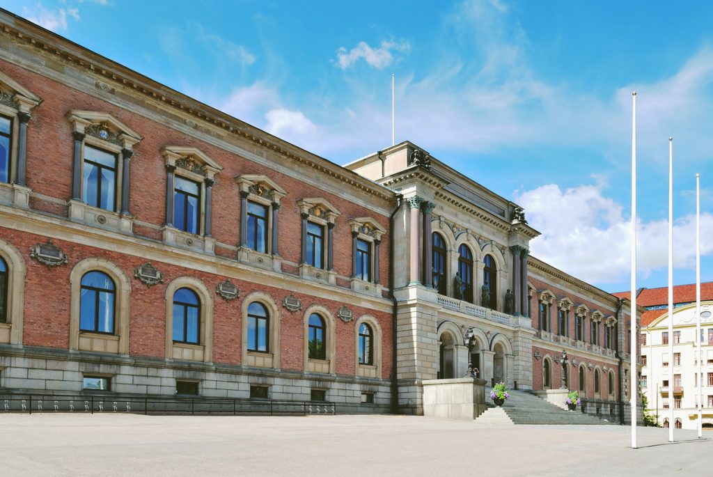 Die monumentale Renaissance-Fassade des Universitätsgebäudes von Uppsala erstreckt sich unter blauem Himmel.