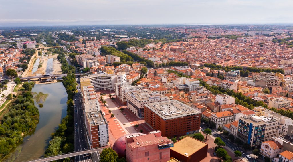 Luftaufnahme von Perpignan mit Fluss, Brücken und dicht bebauter Altstadt.