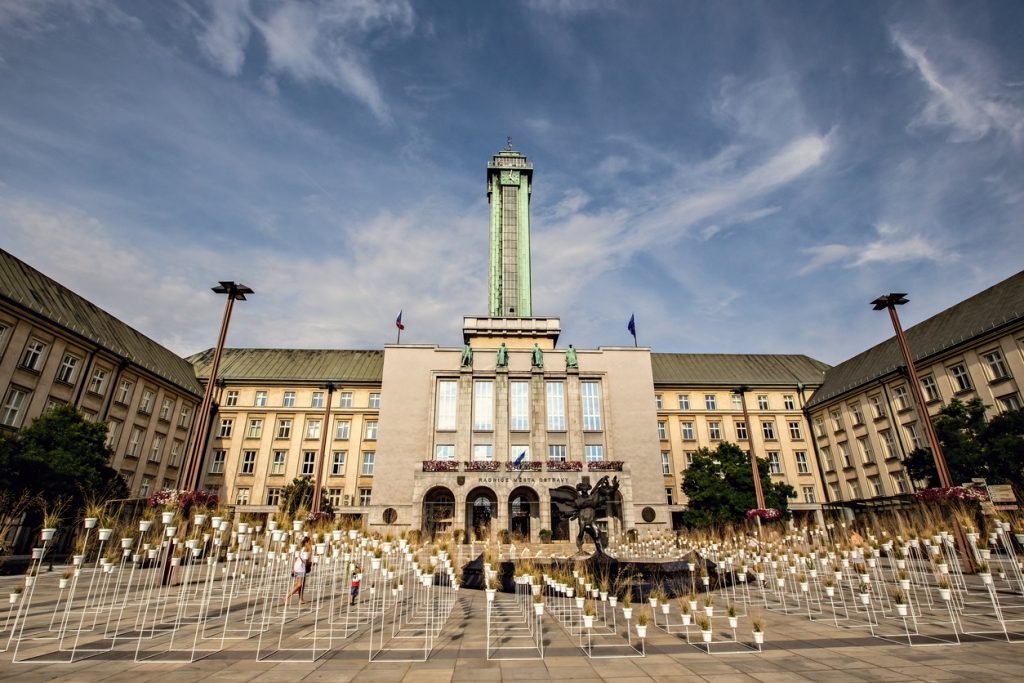 Großes Verwaltungsgebäude mit hohem Turm und vielen weißen Stäben im Vordergrund.