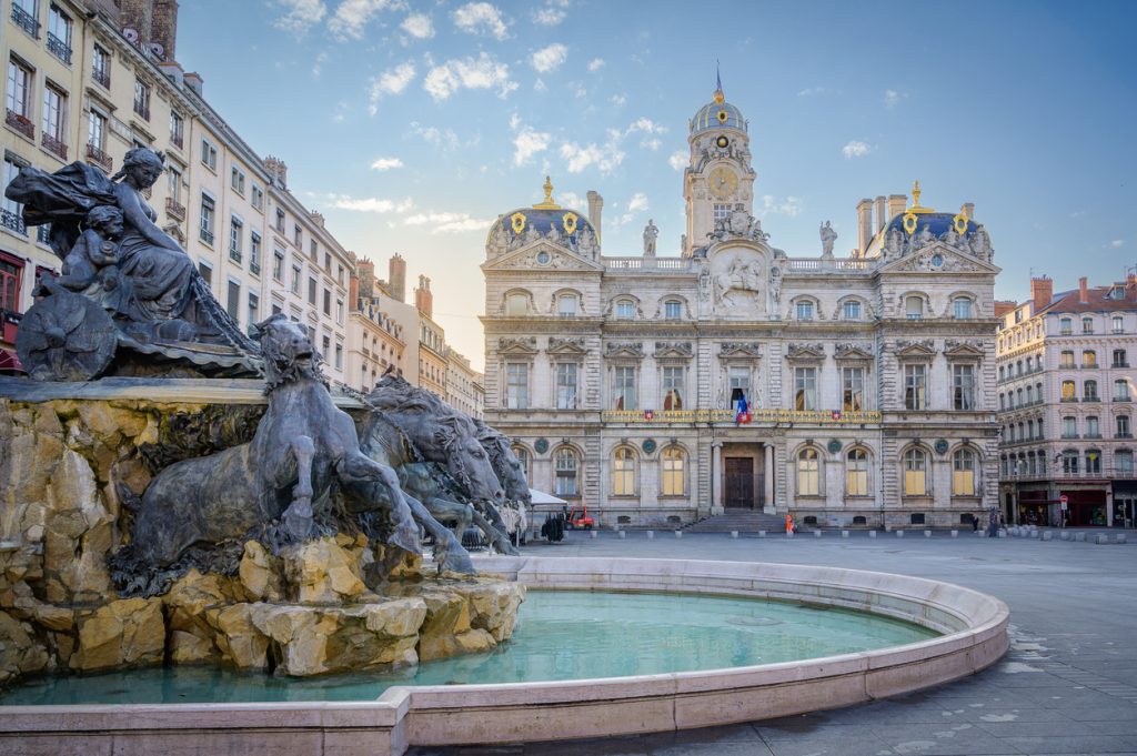 Place des Terreaux in Lyon mit Bartholdi-Brunnen im Vordergrund und dem Hôtel de Ville im Hintergrund.