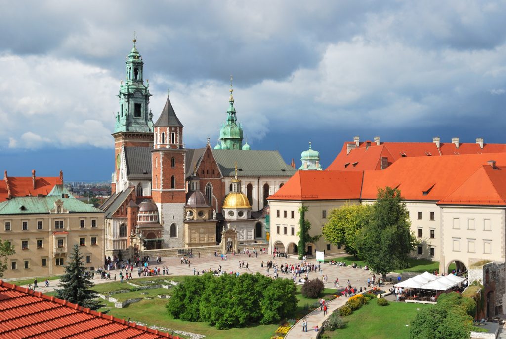 Blick auf die Wawel-Kathedrale in Krakau mit ihren markanten Türmen und der goldenen Kuppel unter einem dramatischen Wolkenhimmel.