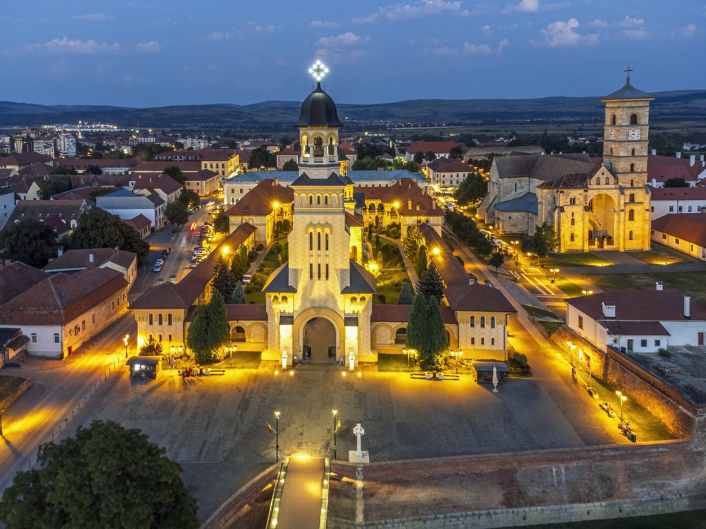 Eine Luftaufnahme zeigt die hell erleuchtete orthodoxe Kathedrale und die Festungsanlagen in der Abenddämmerung.