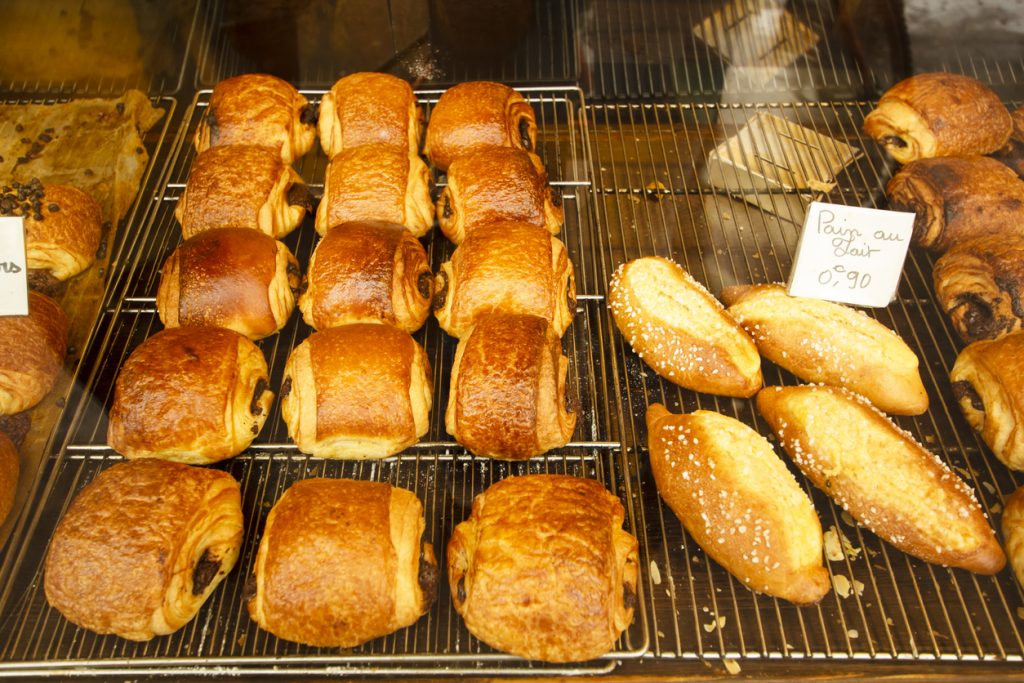 Reihen von Pain au Chocolat und goldbraunem Milchbrot liegen auf einem Backgitter.