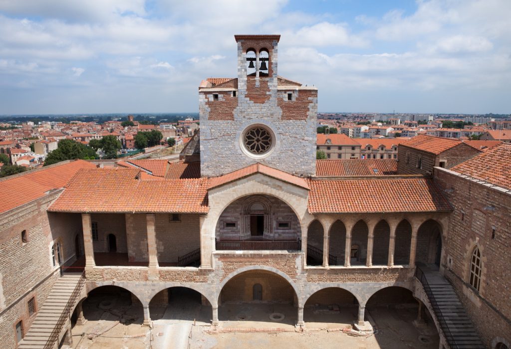 Historischer Innenhof mit Arkaden und Turm über den Dächern in Perpignan.