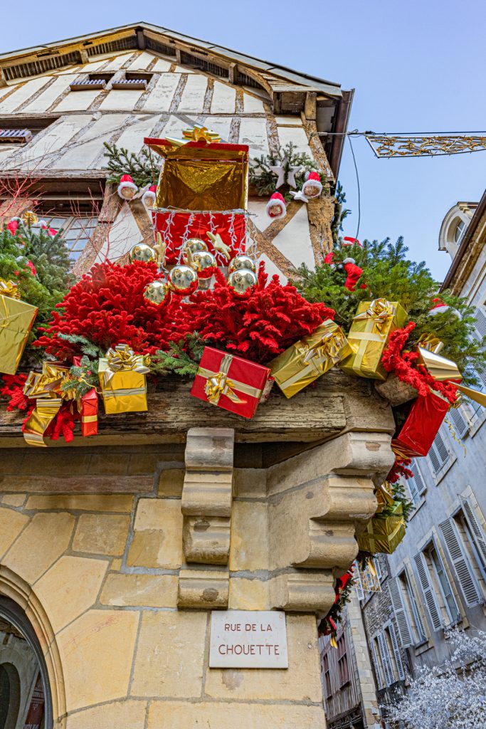 Ein historisches Fachwerkhaus ist üppig mit roten Gestecken, goldenen Geschenken und Weihnachtskugeln geschmückt.
