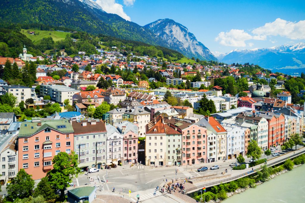 Panorama einer Stadt in einem Tal mit Bergen und blauem Himmel.