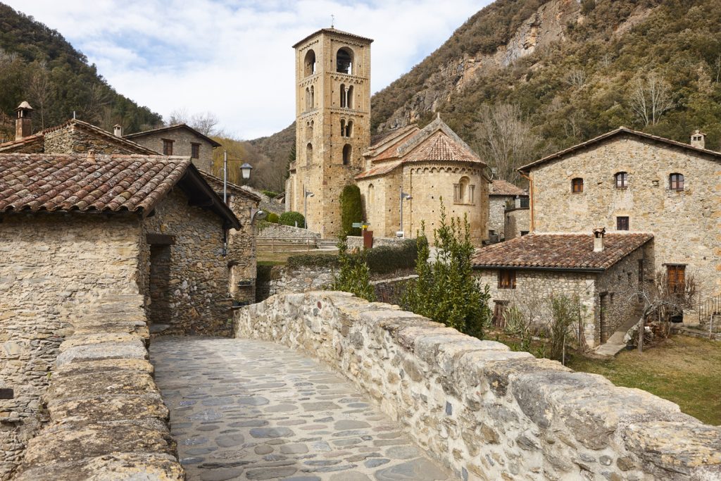 Eine alte Steinkirche mit markantem Glockenturm steht in einem historischen Dorf in der Provinz Girona.