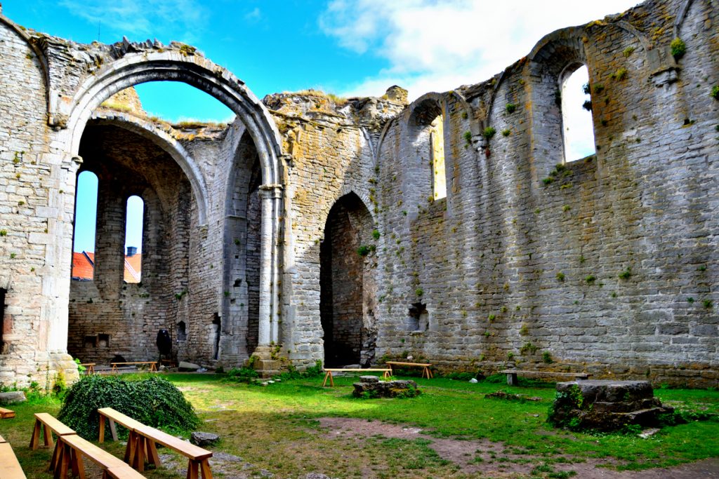 Steinruine mit gotischen Bögen und grüner Wiese im Innenhof.