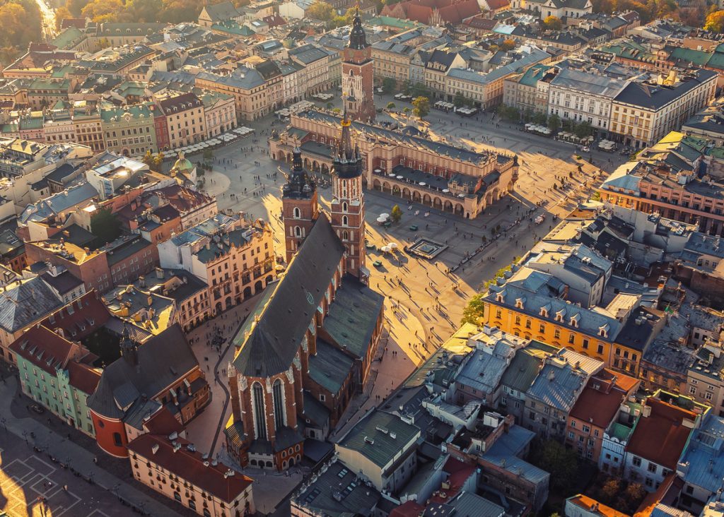 Luftbild von Krakau zeigt den weiten Hauptmarkt mit der Marienkirche und den Tuchhallen im warmen Licht der tiefstehenden Sonne.