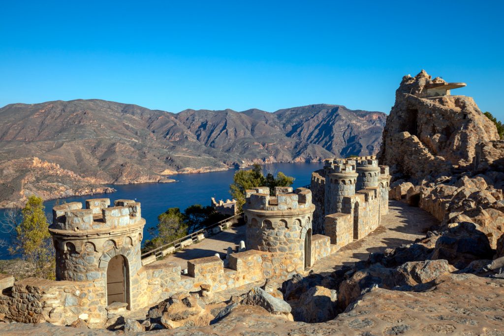 Mittelalterlich wirkende Türme der Küstenbefestigung Castillitos mit Blick auf die tiefblaue Meeresbucht