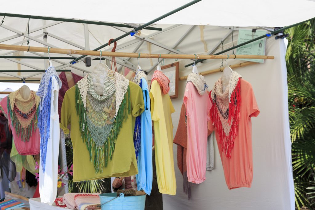 Kleider und Tücher hängen an einem Marktstand auf Mallorca.