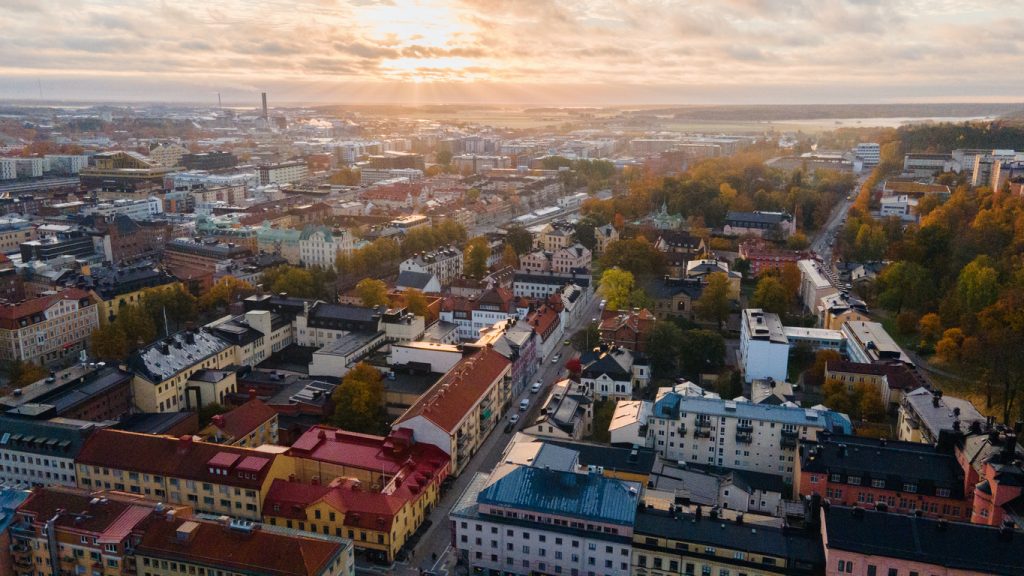 Eine Luftaufnahme zeigt die Stadt Uppsala mit ihren farbenfrohen Häusern im warmen Licht der tiefstehenden Sonne.