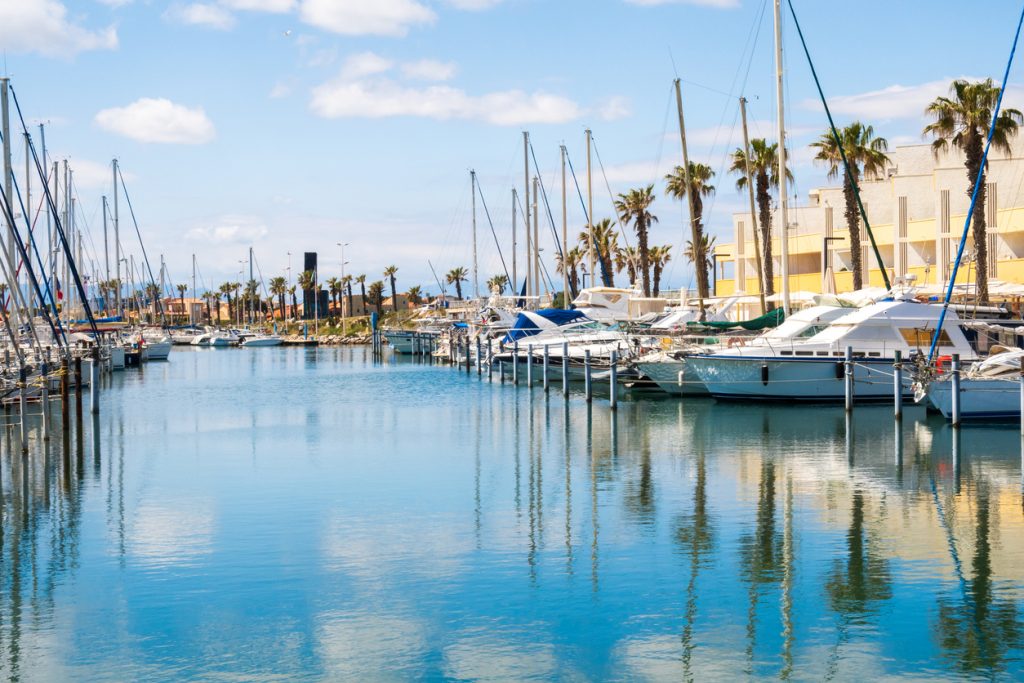 Marina mit Segelbooten, Palmen und ruhigem Wasser nahe Perpignan.