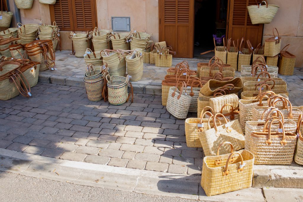 Viele geflochtene Körbe und Taschen stehen vor einem Laden auf Mallorca.