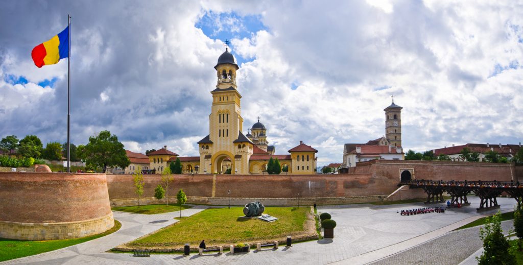 Die orthodoxe Krönungskathedrale von Alba Iulia steht hinter den Festungsmauern unter einem dramatischen Wolkenhimmel.