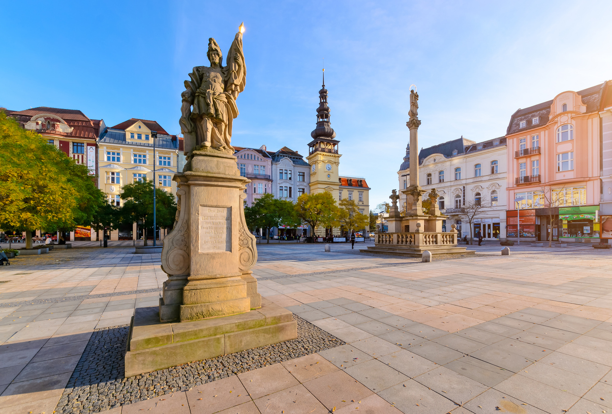 Großes Denkmal auf einem Platz mit historischen Gebäuden und warmem Licht.