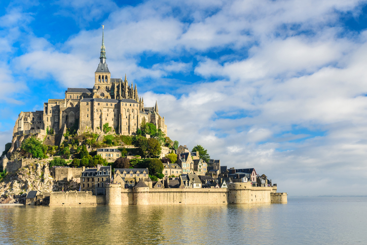 Die berühmte Abtei von Mont-Saint-Michel erhebt sich auf einer felsigen Insel über dem ruhigen Wasser.