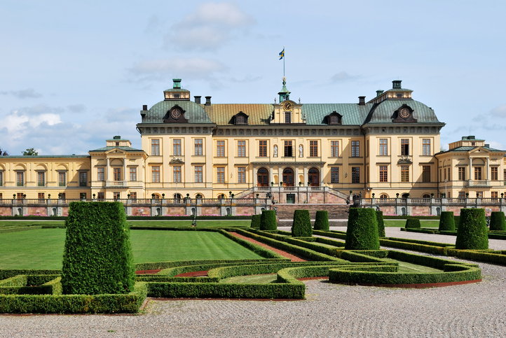 Die imposante gelbe Fassade von Schloss Drottningholm mit seinen barocken Gartenanlagen und symmetrisch geschnittenen Hecken.